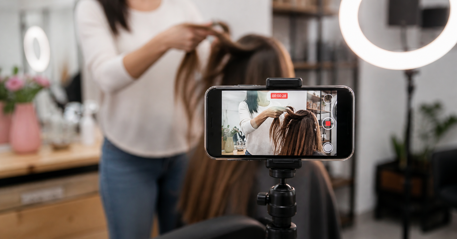 Stylist filming a salon transformation video on a phone with ring light