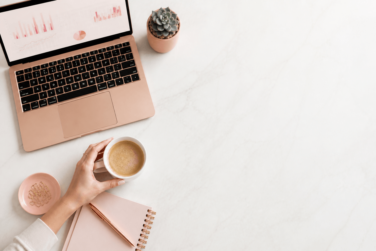 Modern salon owner workspace with laptop showing analytics dashboard and coffee on a clean desk